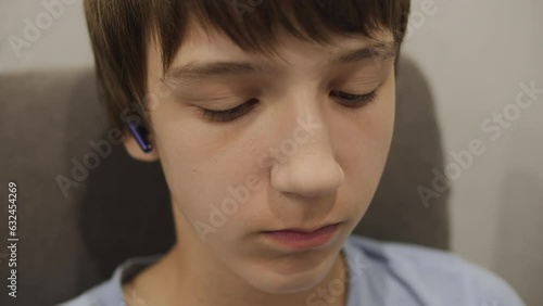 Portrait of caucasian boy wearing headphones looking down at the screen of a digital device