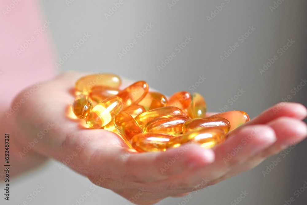 A handful of omega 3 or fish oil capsules in a woman's hand. dietary supplement A handful of omega 3 or fish oil capsules in a woman's hand. dietary supplement