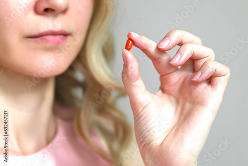Close-up of a Coenzyme Q10 capsule in a woman's hand.