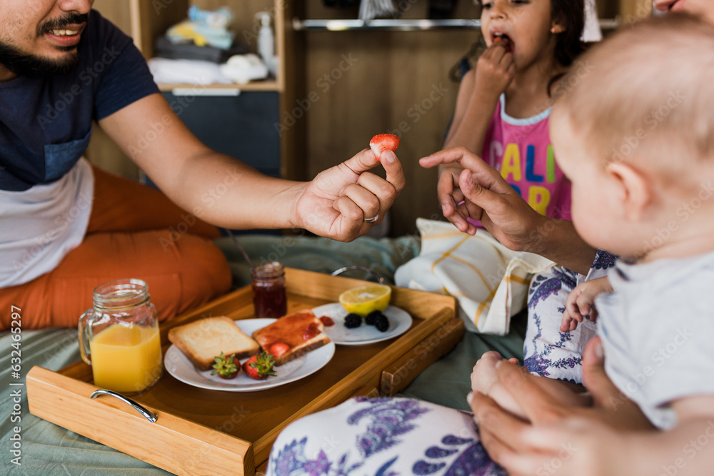 latin family having breakfast on bed at home in Mexico, hispanic mother, father, daughter and son at morning in Latin America latin family having breakfast on bed at home in Mexico, hispanic mother, father, daughter and son at morning in Latin America