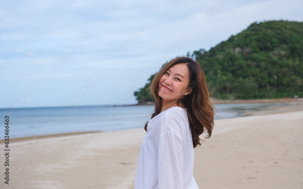 Portrait image of a beautiful young asian woman while strolling on the beach with the sea and blue sky Portrait image of a beautiful young asian woman while strolling on the beach with the sea and blue sky