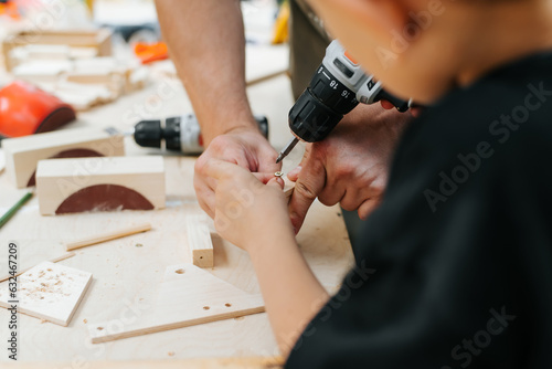 A father teaches his son how to work with wood, a boy holding a screwdriver close-up