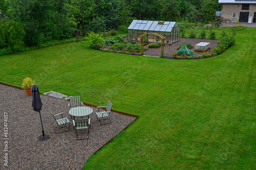 Looking out over back garden with seating area and green house photo