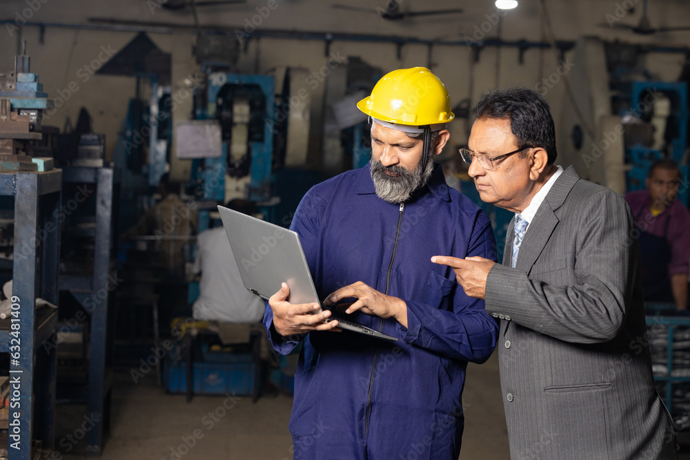 worker using laptop while discussing with factory owner worker using laptop while discussing with factory owner