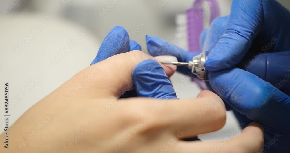 Process of hardware manicure for client in beauty salon closeup. Manicurists use electric nail drill to remove polish and cuticles from nails Process of hardware manicure for client in beauty salon closeup. Manicurists use electric nail drill to remove polish and cuticles from nails