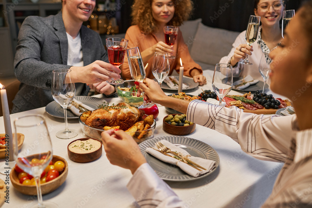 © Seventyfour - African American girl with flute of champagne toasting with glass of red wine held by young smiling man sitting in front of her by table