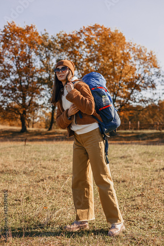 Full length of female traveler with backpack enjoying adventure in autumn in nature  © Dzmitry