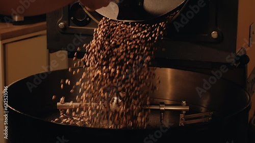 Production of fresh fried coffee beans. Roast master opens roasting coffee machine. Roasted coffee beans fall down on a cooling plate of an oven