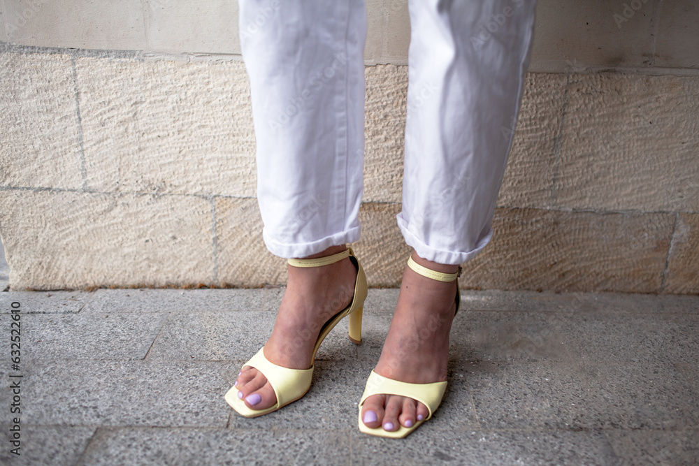 clpde-up of female legs weared the yellow sandels and white jeans