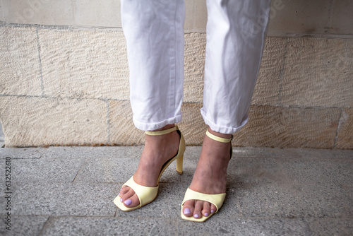 clpde-up of female legs weared the yellow sandels and white jeans