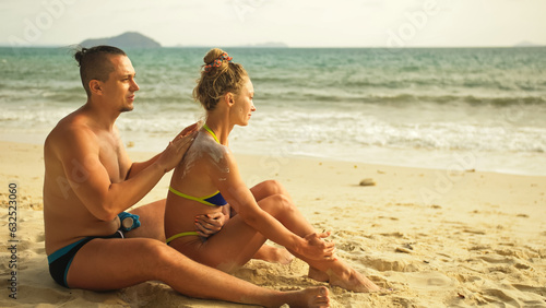 Carefree barefoot loving couple having sun block. Woman to put sunscreen man. Young girl and guy in hugging using sun cream. Concept rest tropical resort, traveling tourism happy summer holidays