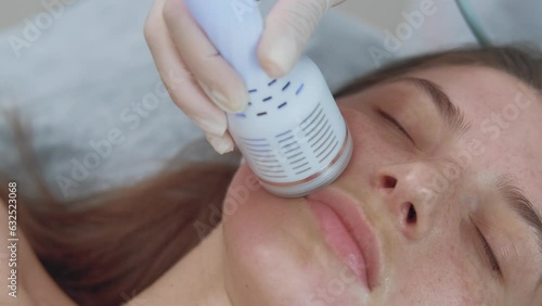 Close up footage of cosmetologist using cryotherapy lifting massage to restore and elevate patient's skin. photo