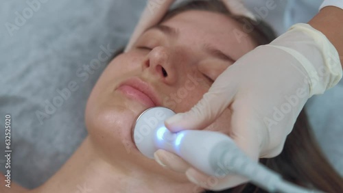 Footage of cosmetician makes ultrasound facial massage. Face beauty treatment. photo