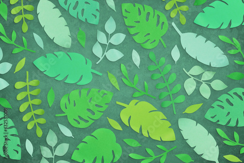 Composition of cut paper tropical palm leaves, jungle Monstera and banana leaves. Handmade nature mockup, summer art collection isolated on green background. Top view, flat lay, full cover, close up
