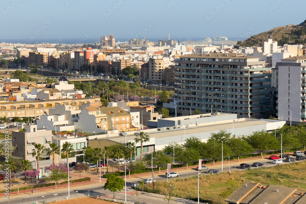 Buildings and houses in city. Sagunto Town, view of city from mountain. Roofs of houses and townhouses roofs view from of Sagunto Castle, Spain. Background the Port of Sagunto and Mediterranean Sea. Buildings and houses in city. Sagunto Town, view of city from mountain. Roofs of houses and townhouses roofs view from of Sagunto Castle, Spain. Background the Port of Sagunto and Mediterranean Sea.