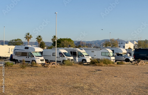 Campervan in camp parking near beach at coastline. Family rv camper van vehicle at seaside. Rving motorhome lifestyle travel to sea. Travel on Campervan along Spain coast. Caravaning Parking. Camping