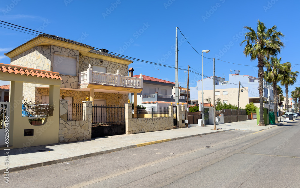 Gate and brick wall of fence on street sidewalk. Villa with Garden. Fence at a suburb house. Design house and luxury facilities. Garden Home building Exterior. Luxury Villa with palm trees in garden.