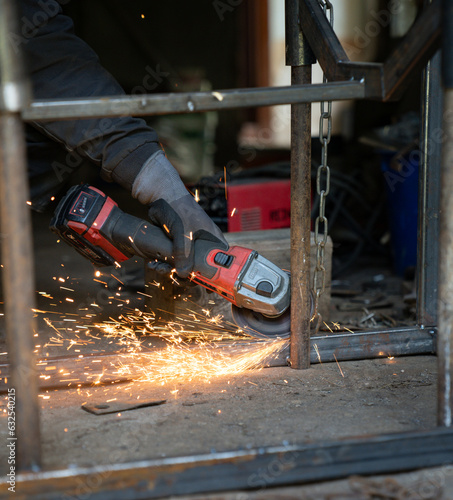 The man holds a flexi in his hands and cuts a metal plate