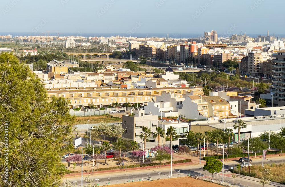 Buildings and houses in city. Sagunto Town, view of city from mountain. Roofs of houses and townhouses roofs view from of Sagunto Castle, Spain. Background the Port of Sagunto and Mediterranean Sea.