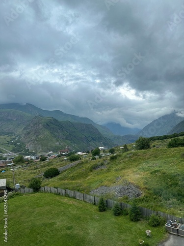 A View to Infinity: The Kazbegi Mountains Rise Above the Clouds, surrounding the small town of Kazbegi Mkinvartsveri in Georgia in a cloudy day in summer, Gudauri gergeti trinty church, ananuri
