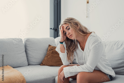 Depressed or tired teen girl feeling stress headache hurt pain sitting alone at home, upset sad heartbroken young woman regret pregnancy or abortion, troubled with problem or psychological trauma 