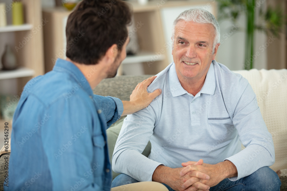 Obraz premium grown son sit on couch relax talking with senior dad