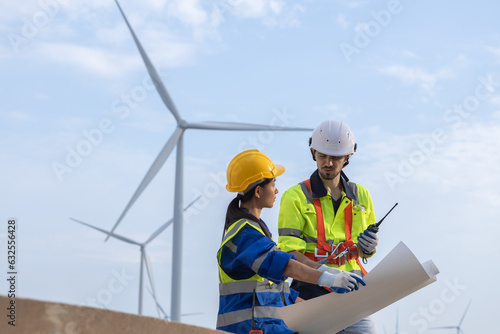 Wind turbine technician checking and maintenance at turbine station. Man and woman engineer working at energy wind generator. clean energy source.