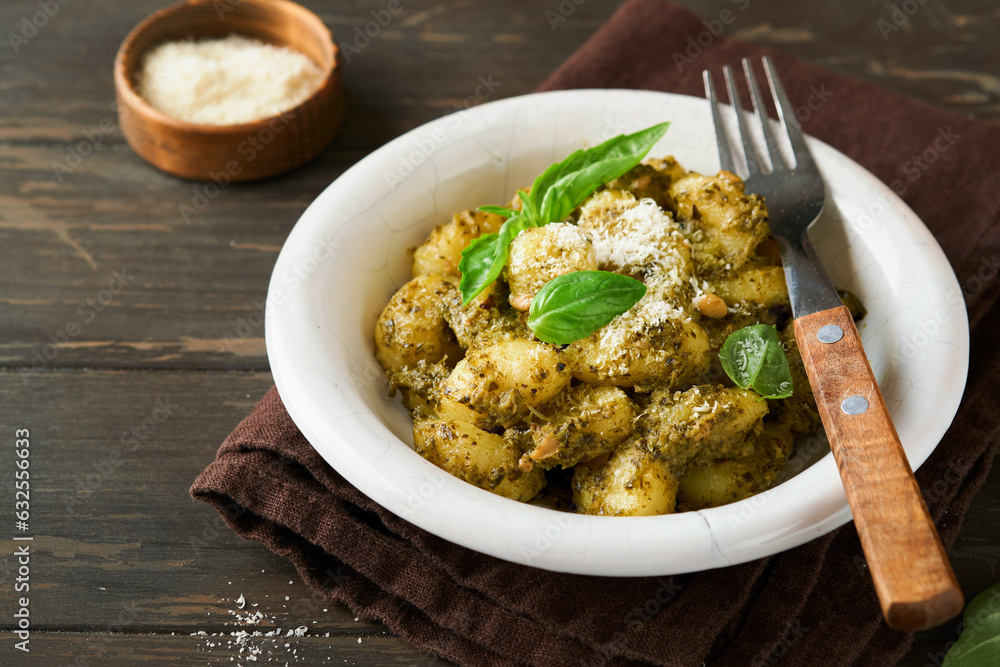 Potato gnocchi. Traditional homemade potato gnocchi with sauce pesto, kitchen table and basil on old dark rustic turquoise kitchen table. Traditional Italian food. Top view.