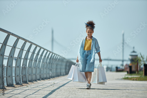 African American little girl with shopping bags walking outdoors