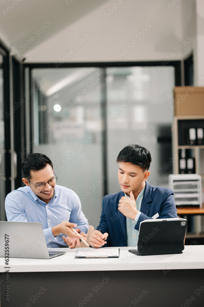 Two Asian business workers talking on the smartphone, tablet and using laptop at the office. Two Asian business workers talking on the smartphone, tablet and using laptop at the office.