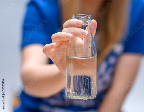 Szklana butelka z wodą pitną trzymana w dłoni 