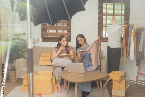 Startup small business owner working with computer at workplace. Freelance two woman seller check product order. Online selling. E-commerce. Behind the scene concept