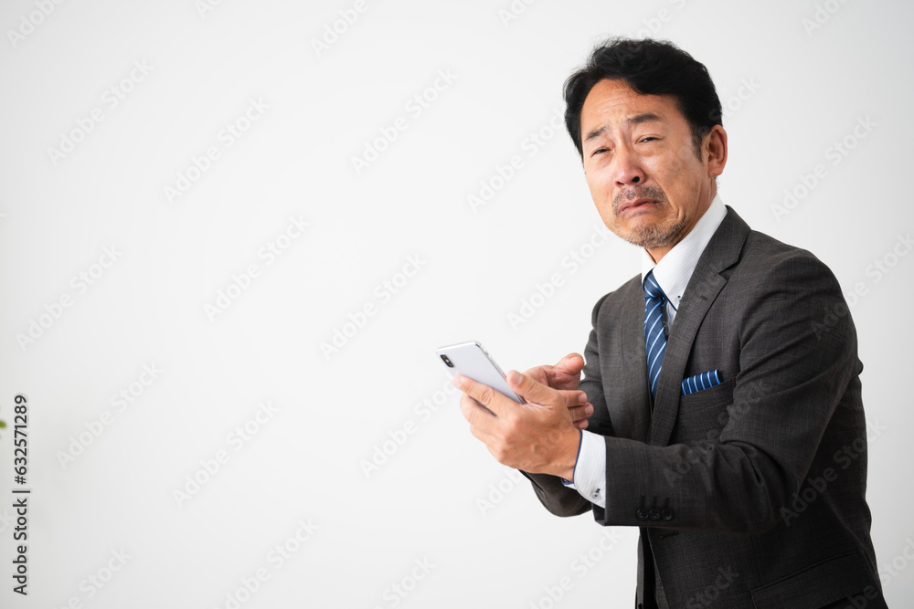 スマートフォンを持って悲しんでいるミドル男性 ビジネスイメージ スマートフォンを持って悲しんでいるミドル男性 ビジネスイメージ