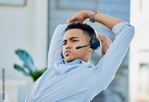 Tired, stretching and man in call center with stress for telemarketing, customer service and sales consulting. Lazy, uncomfortable and male agent on a break for burnout, fatigue or bored at help desk