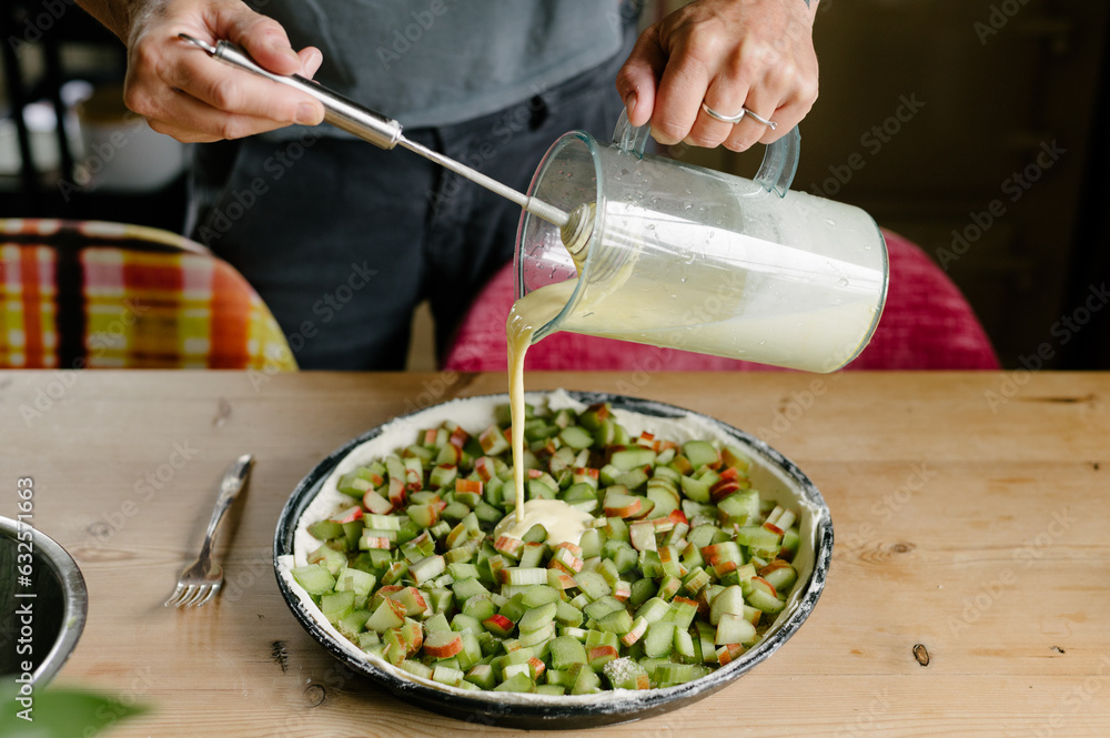 Unrecognizable man baker standing near pie dough and ingredients pan and pouring sauce from glass jar Unrecognizable man baker standing near pie dough and ingredients pan and pouring sauce from glass jar