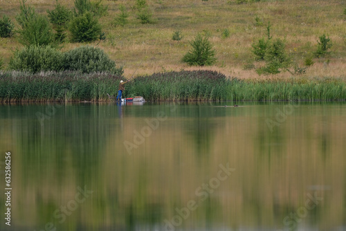 nature, lake, ducks swim, a man on the opposite bank catches fish, a lot of green grass © Юрий Горид