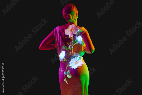 Back view. Half-length image of young relaxing woman in white dress posing in neon light isolated on dark mode background.