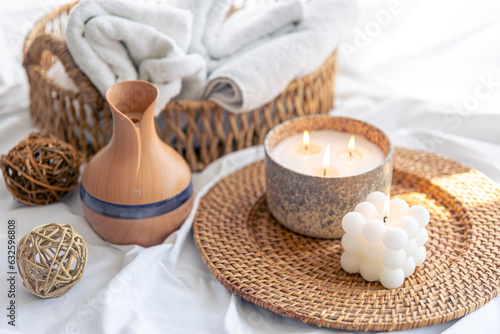 Spa composition with aroma diffuser and candles on a blurred background.