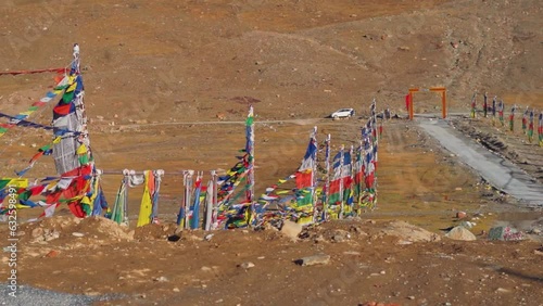 Slow motion shot of prayer flags waving in the wind in front of the snow covered Himalayan mountains at Kunzum Pass on the way to Kaza from Manali in Himachal Pradesh, India. Prayer flags at Kunzum.	