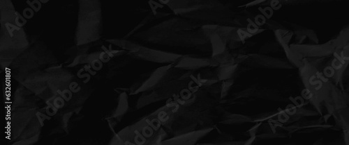 Texture of black crumpled paper, black crumpled paper texture in low light background, dark paper background with chaotic bends, black wrinkled paper texture.