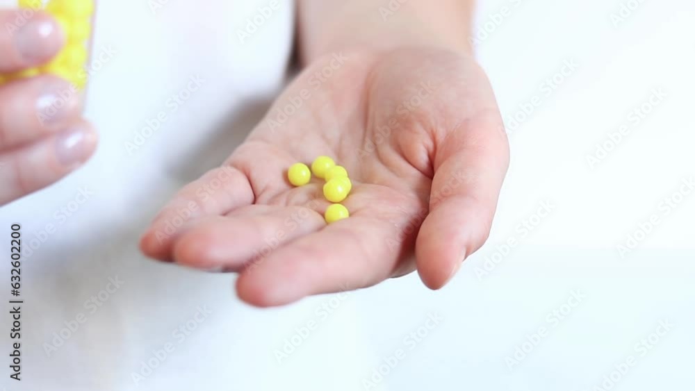 Pour yellow pills from a glass bottle into a woman's hand. Vitamin C, ascorbic acid. Vitamins and dietary supplements close-up Pour yellow pills from a glass bottle into a woman's hand. Vitamin C, ascorbic acid. Vitamins and dietary supplements close-up