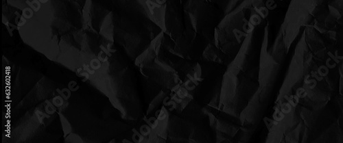 Texture of black crumpled paper, black crumpled paper texture in low light background, dark paper background with chaotic bends, black wrinkled paper texture.