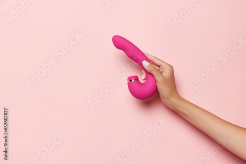 Female hand with vibrator, medical massager over pastel pink background. Image for sex shop. Concept of woman health, medicine, ad