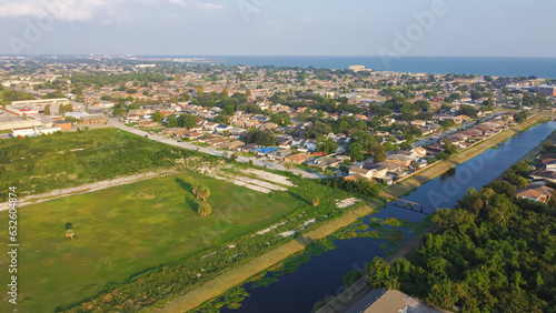 Large vacant land near Farrar Canal with residential houses, duplex townhomes, lush green trees in Little Woods neighborhood toward Lake Pontchartrain in East New Orleans, Louisiana, USA