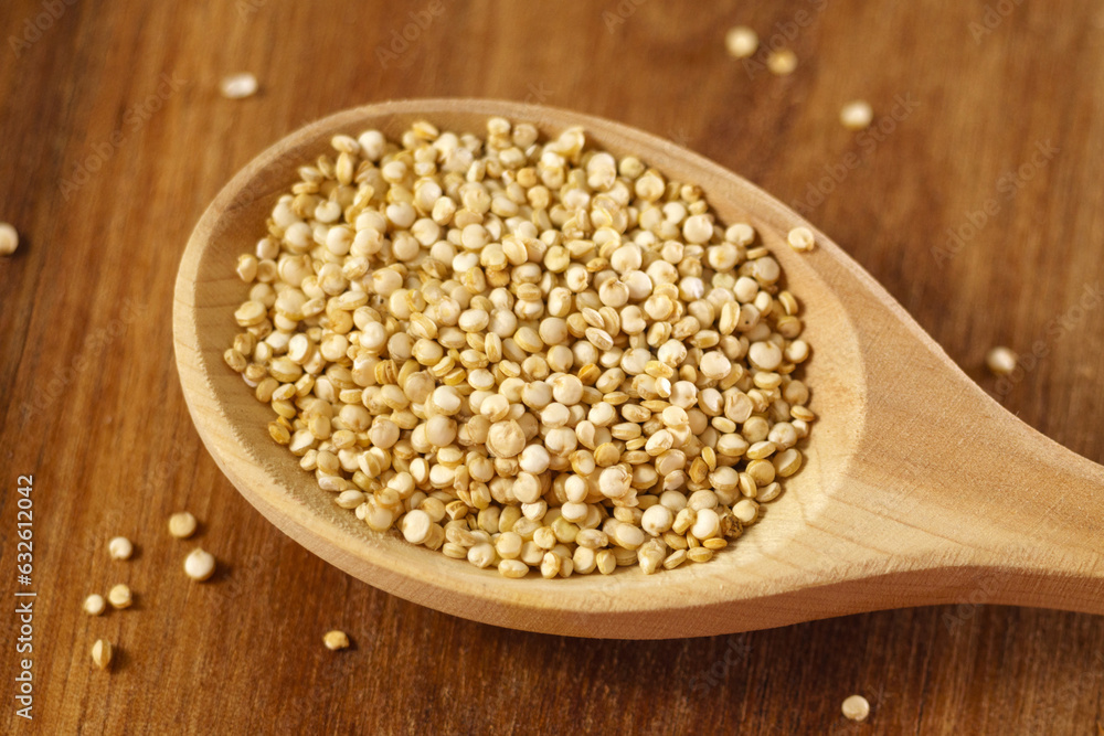 Raw quinoa kernels are heaped into a wooden spoon. Cereal seeds close-up. Macro Raw quinoa kernels are heaped into a wooden spoon. Cereal seeds close-up. Macro
