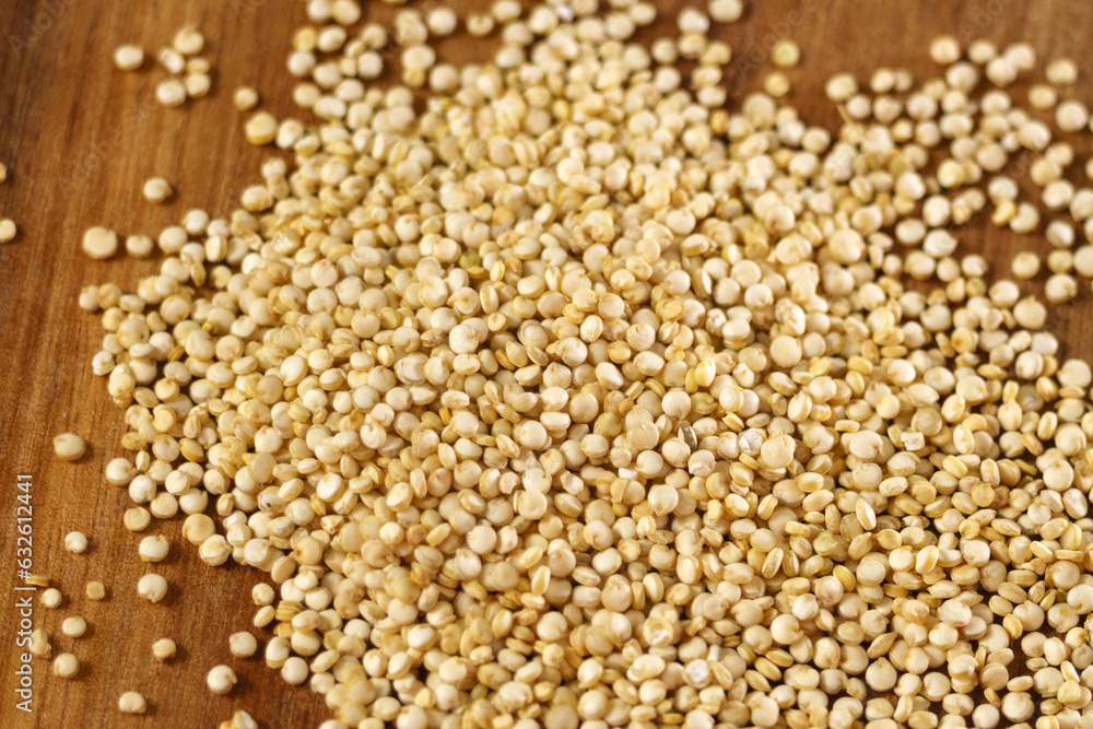 Raw quinoa kernels are heaped into a wooden spoon. Cereal seeds close-up. Macro Raw quinoa kernels are heaped into a wooden spoon. Cereal seeds close-up. Macro