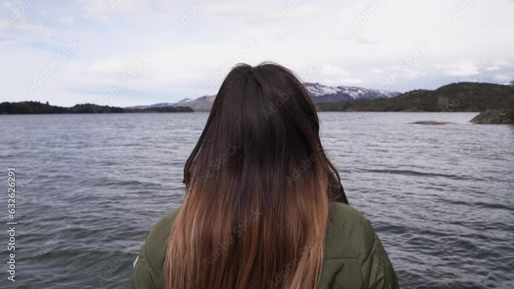 Vacations. Closeup view of a young woman with brown hair contemplating the calm lake and mountains in the horizon. Vacations. Closeup view of a young woman with brown hair contemplating the calm lake and mountains in the horizon.