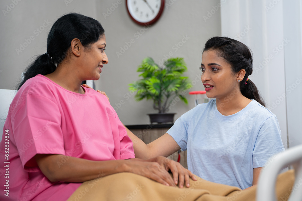 Young indian caring daughter consoling to sick mother by holding hands at hospital - concept of family caring or support, medical treatment and relationship bonding. Young indian caring daughter consoling to sick mother by holding hands at hospital - concept of family caring or support, medical treatment and relationship bonding.