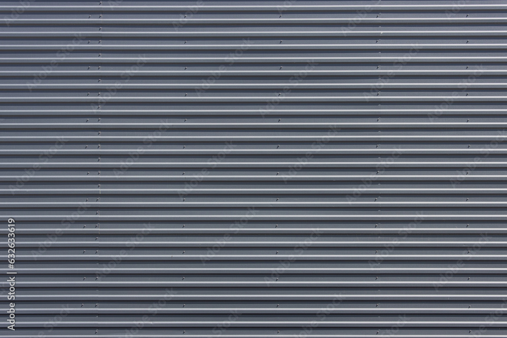Large flat surface of a building clad in gray metal roof sheets Large flat surface of a building clad in gray metal roof sheets