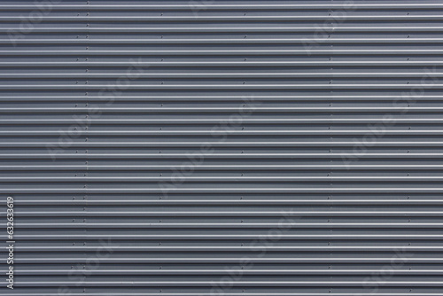 Large flat surface of a building clad in gray metal roof sheets